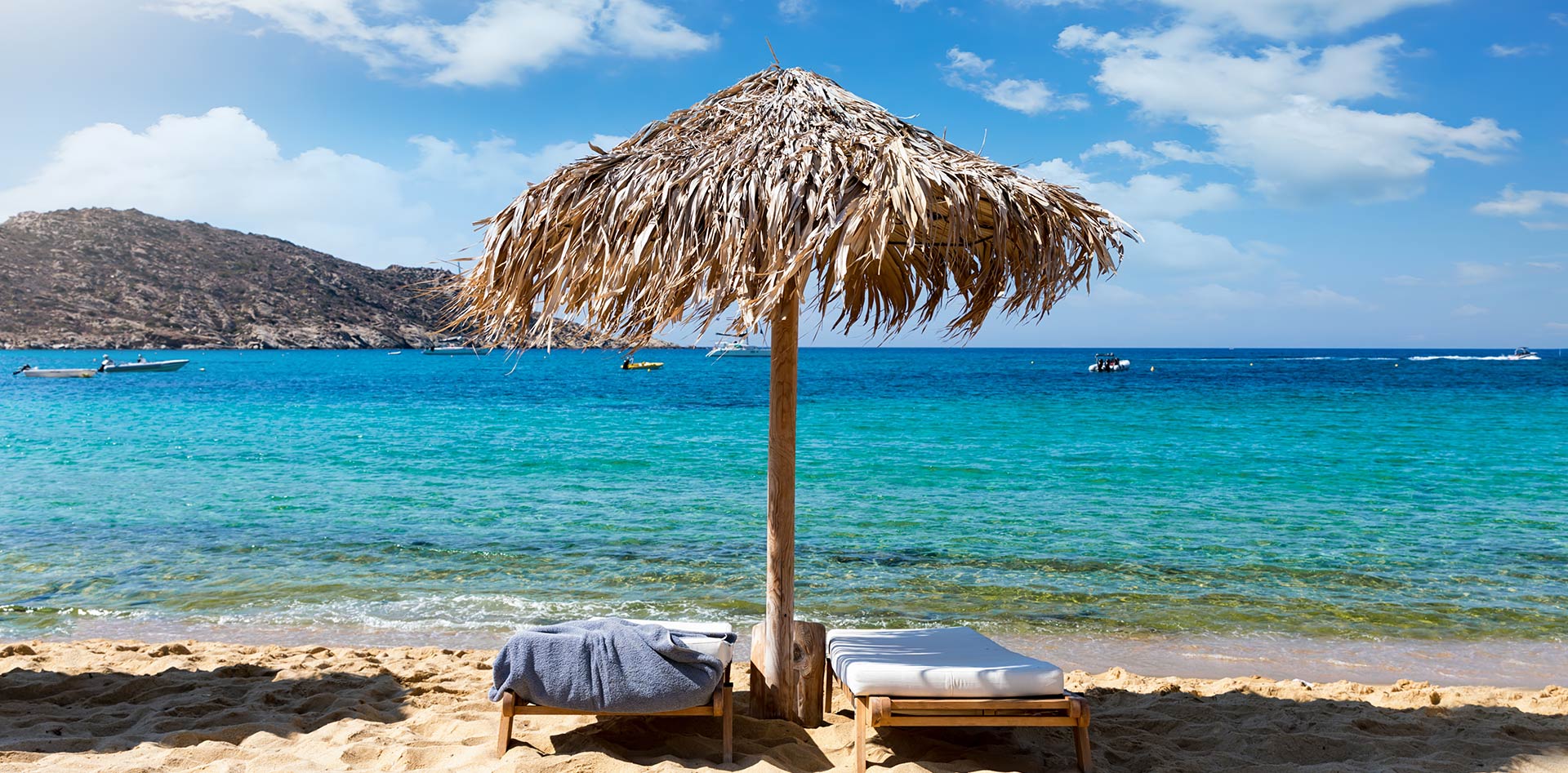 Two lounge chairs under an umbrella on a beach