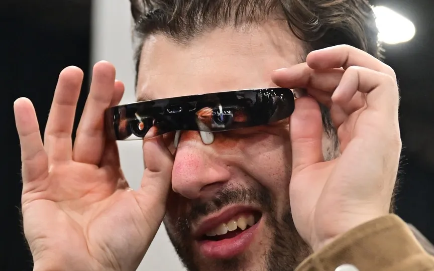A man samples the Vixion 01 autofocus eyewear that automatically adjusts focus, supporting resolving challenges from eye strain and age during the CES 2024. (AFP)