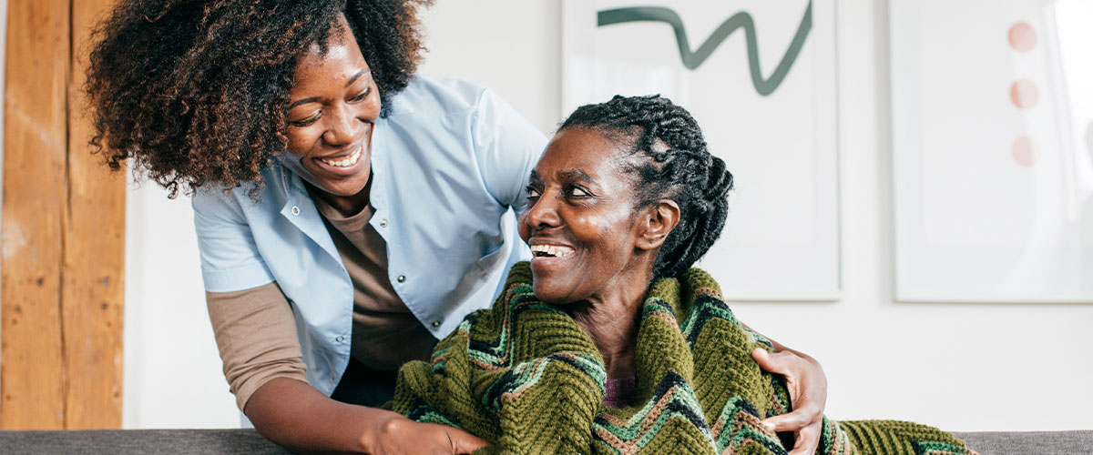 new_family_caregivers_post Nurse putting a blanket around a senior woman