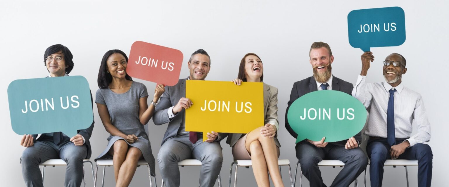 43f1bc11-whyseniorlivingcareer-1536×640 group of people in the workforce holding "join us" signs