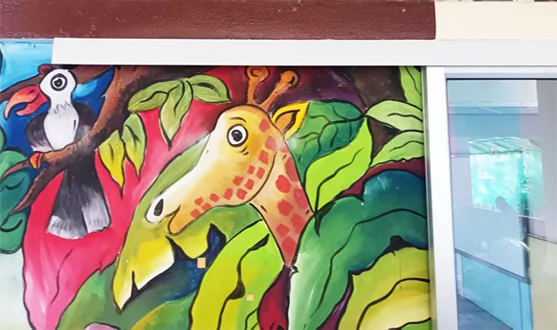 Mural colorido de una jirafa y un tucán pintado sobre vidrio junto a una puerta corredera.