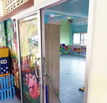 Puerta corredera nueva de vidrio y aluminio con dibujos animados que da acceso a un aula renovada.