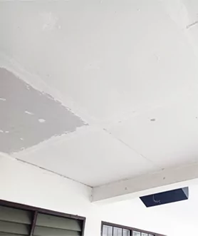 Techo de un aula con paneles de yeso recién reparados.