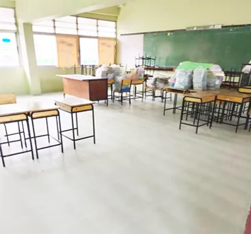 Aula con suelo nuevo, pupitres apilados a un lado y materiales sobre las mesas.