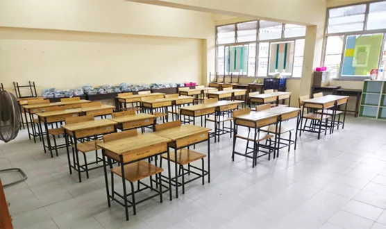 Aula terminada con pupitres de madera dispuestos sobre baldosas blancas nuevas.