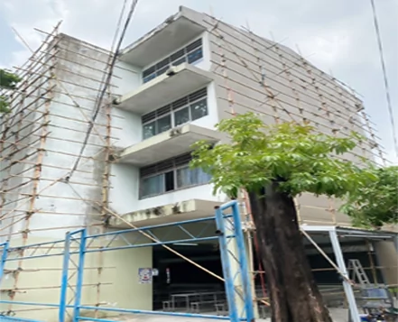 Edificio escolar rodeado de andamios de bambú durante la preparación de la fachada.