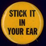 Late 1960s-early 1970s antiestablishment button as used on Nicky Marotta's leather jacket in TIMES SQIUARE (1980) Text: STICK IT IN YOUR EAR