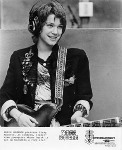 Robin Johnson as Nicky Marotta in the WJAD studio. ITC variant of TIMES SQAURE press photo TS-69-34A. Text: ROBIN JOHNSON portrays Nicky Marotta, an aimless, street- wise youngster whose heart is set on becoming a rock star. TIMES SQUARE™ ITC ENTERTAINMENT AN acc COMPANY Permission is hereby granted to newspapers and other periodicals to reproduce this photograph for publicity or advertising except for the endorsement of products. This must not be sold leased or given away. Printed in U.S.A.