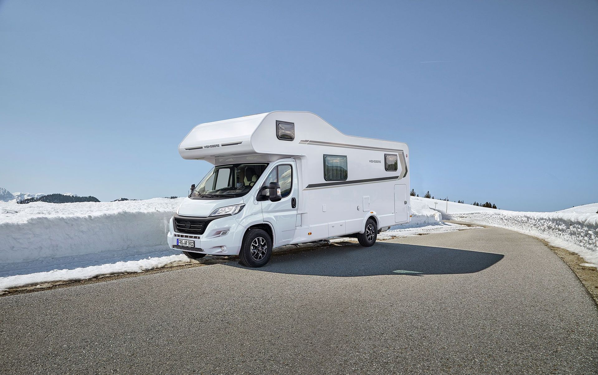 Alkoven Wohnmobil auf asphaltierter Straße, in einer Schneelandschaft – großes Wohnmobil mieten Kempen