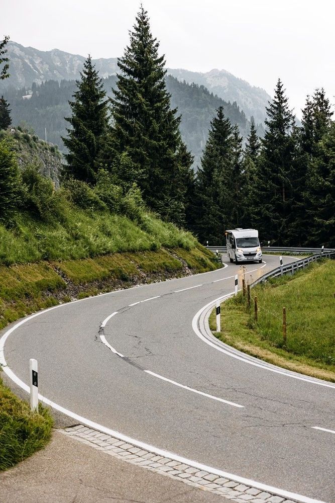 Der Freedom fährt auf einer Straße umgeben von Natur, wie Tannen und Bergen.