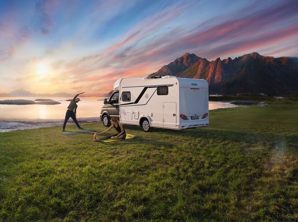 Paerchen vor Wohnmobil beim Sonnenaufgang