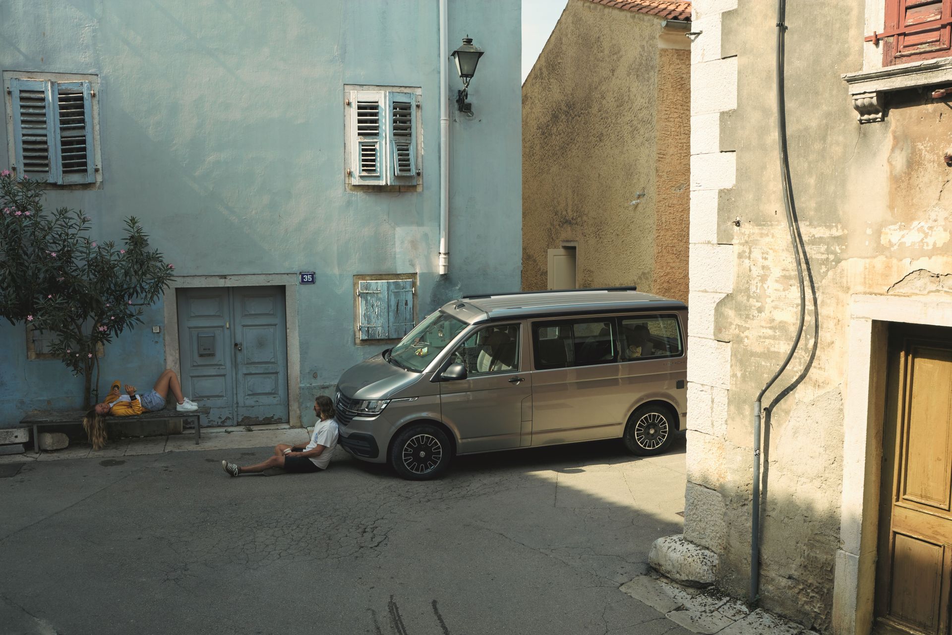 VW Camper in einer engen, leeren Gasse mit Häusern südländischen Touchs