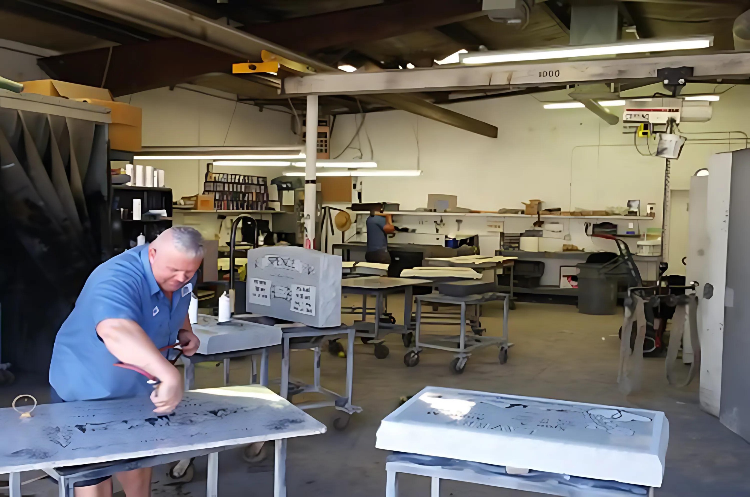 A craftsperson finishing a granite memorial by hand in the Rocky Mountain workshop.