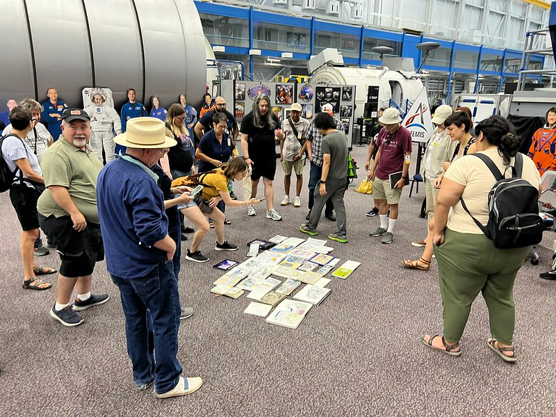 People standing in a circle looking at sketches on the ground