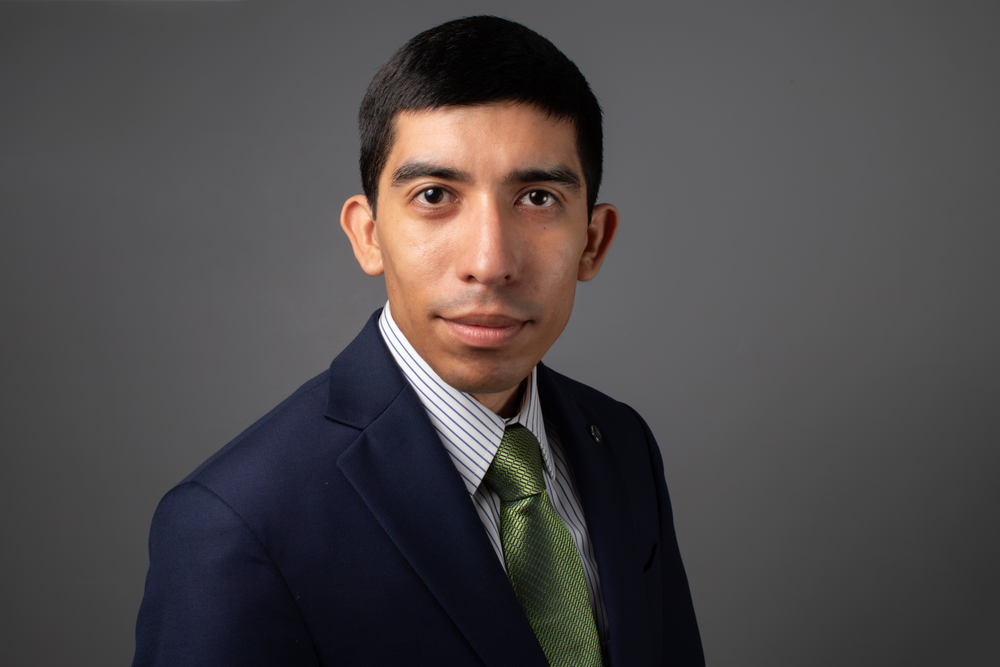 An official headshot of a man wearing a blue suit and green tie.