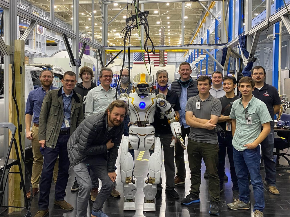 A group of people poses with a human-like robot.