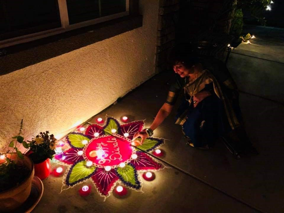 A person dressed in ceremonial clothing next to colorful bright lights shaped like a lotus on the ground.