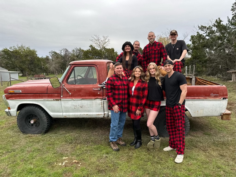 A family poses for a group photo in the bed of an old pickup truck.