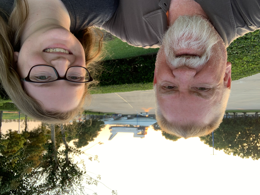 A young woman and her father take a selfie in front of Space Center Houston's 747-mounted space shuttle.