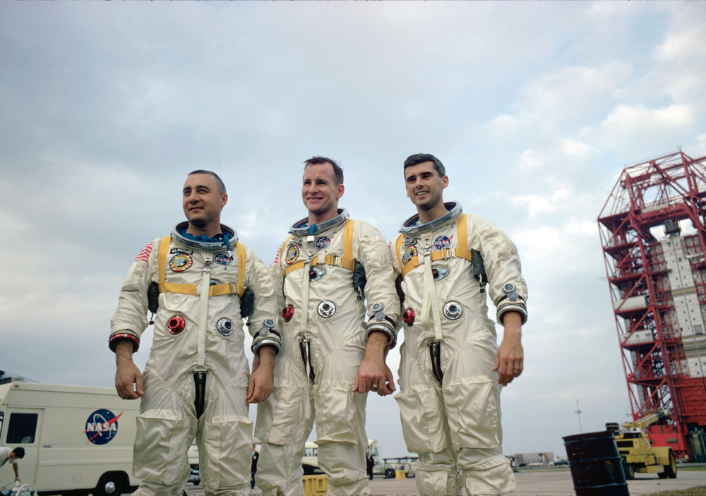 An image of three people outside wearing white space suits.