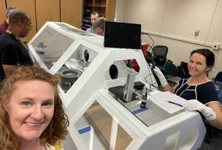 The OSIRIS-REx team practices for sample return at Johnson with a mock-up glovebox in October 2022. From front left going clockwise are Michelle Thompson, OSIRIS-REx contact pad analysis deputy lead and professor of planetary sciences at Purdue University, West Lafayette, Indiana and Johnson team members from the ARES division Christopher Snead and Kevin Righter, OSIRIS-REx deputy sample curators; Wayland Connelly, astromaterials curation engineer; Lindsay Keller OSIRIS-REx contact pad analysis lead, and Nicole Lunning, OSIRIS-REx sample curator. Credit: Purdue University/Michelle Thompson