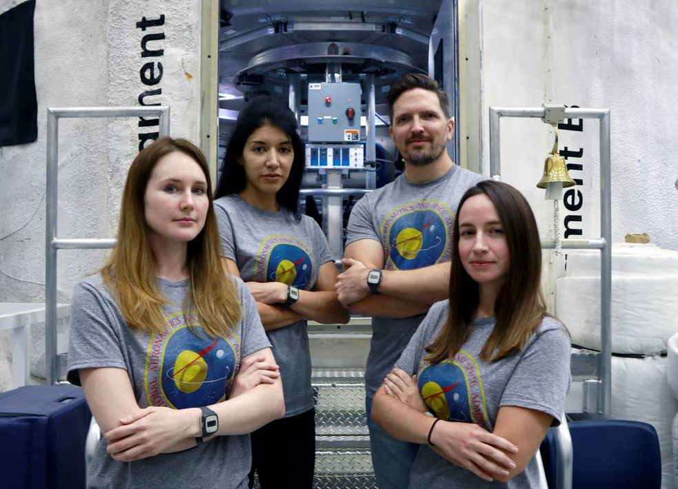 The new crew for the upcoming mission of NASA’s Human Exploration Research Analog, or HERA, stands in front of the habitat that will be their home for 45 days. From left to right: Lauren Cornell, Monique Garcia, Christopher Roberts, and Madelyne Willis. Credits: NASA