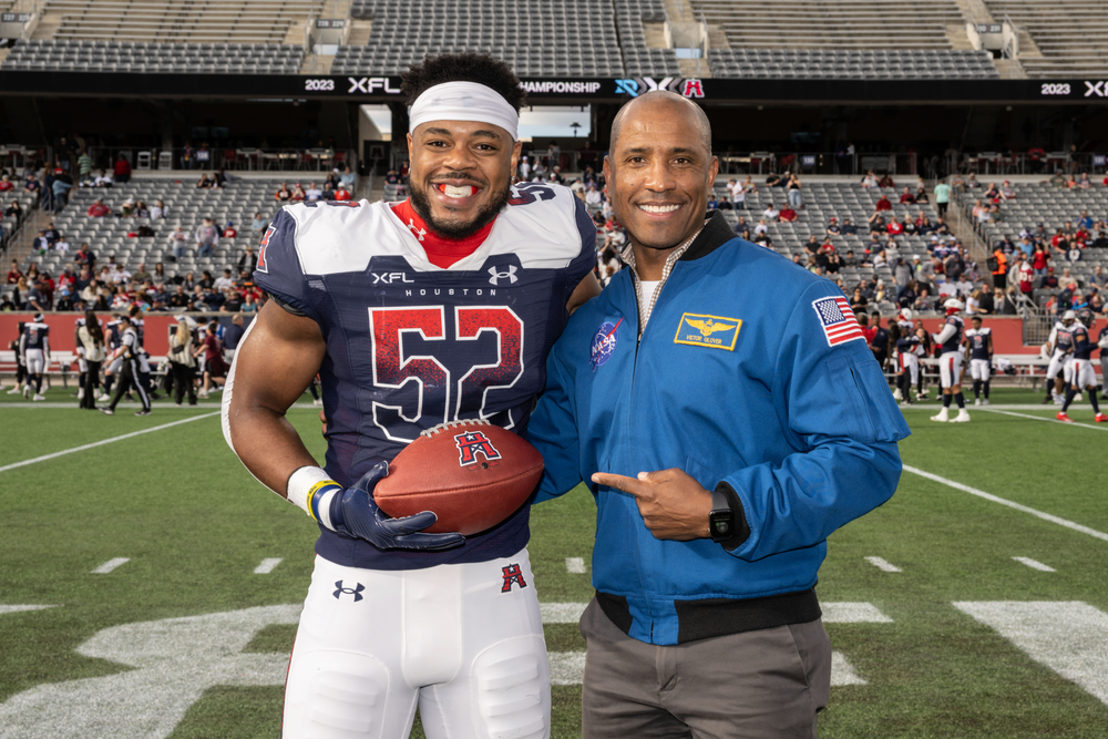 Artemis II pilot Victor Glover (right) presents the game ball to Houston Roughnecks linebacker Emmanuel Ellerbee (left) after the XFL South Division Championship game at the University of Houston.