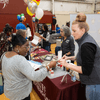 Groups of people enjoy a variety of indoor and outdoor exhibits and displays during a safety and health fair.