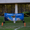 A group of people gathered outside on the lawn during a turkey launch. 