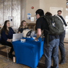 People gather together around a television in a cafeteria.