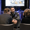 People gather together around a television in a cafeteria.