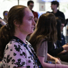 People gather together around a television in a cafeteria.