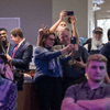 People gather together around a television in a cafeteria.