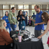 People gather in an auditorium lobby to visit exhibit tables.