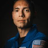 A person posing in a blue spacesuit in front of a black background. 