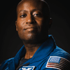 A person posing in a blue spacesuit in front of a black background. 