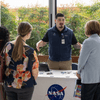 People enjoy exhibit tables, lunch, and a band at an employee event.