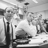 Astronauts (left to right) Edgar Mitchell, Jack Schmitt, Engle, Duke, McCandless and Deke Slayton gathered around the Capcom console during the LOI maneuver. Image Credit: NASA