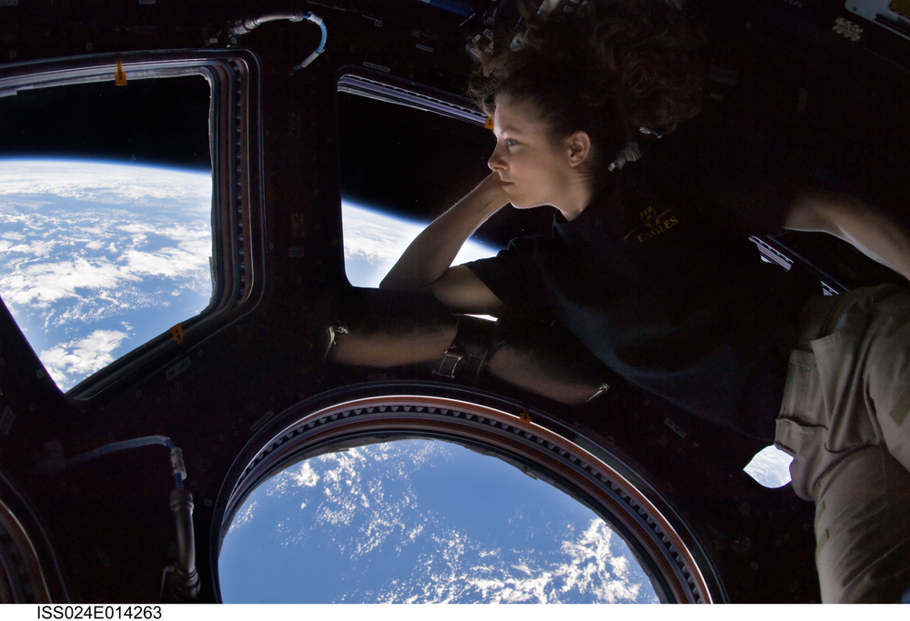 A female astronaut looks out from the windows of the cupola on the International Space Station.