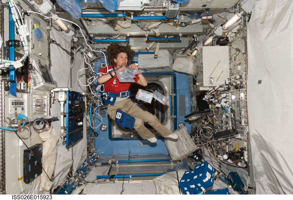 A female astronaut breathes into a plastic bag while floating on the International Space Station.