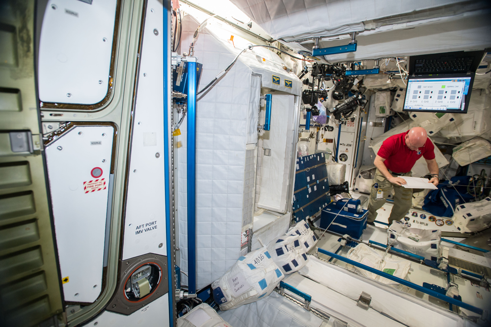 An astronaut holds a clipboard as he collects samples from different surfaces within the International Space Station.