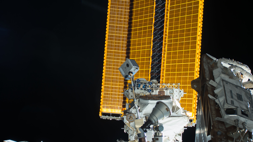 View of a truss in space with solar arrays in the background.