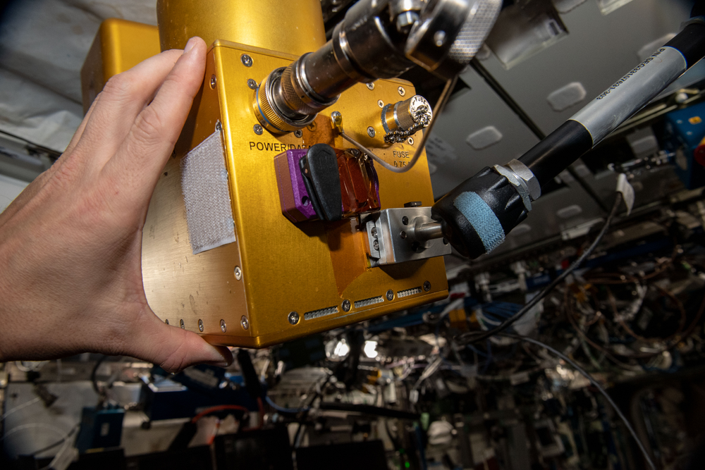 Image of a hand holding a yellow rectangular box. 