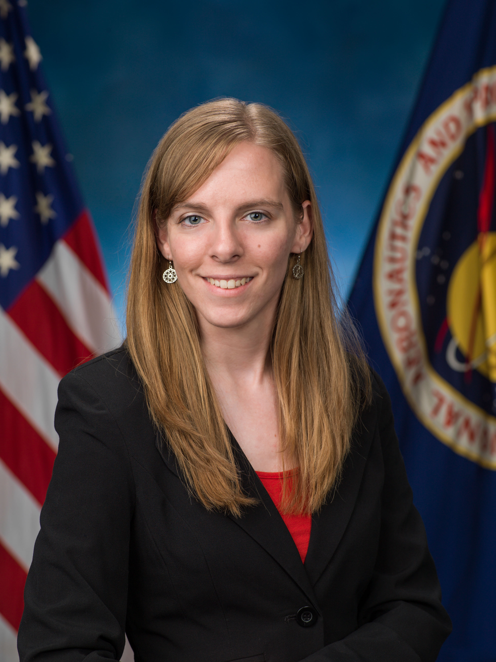 Professional headshot of a young woman with flags in the background.