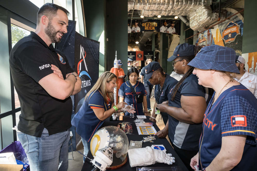 People gather at a booth with information about space exploration.