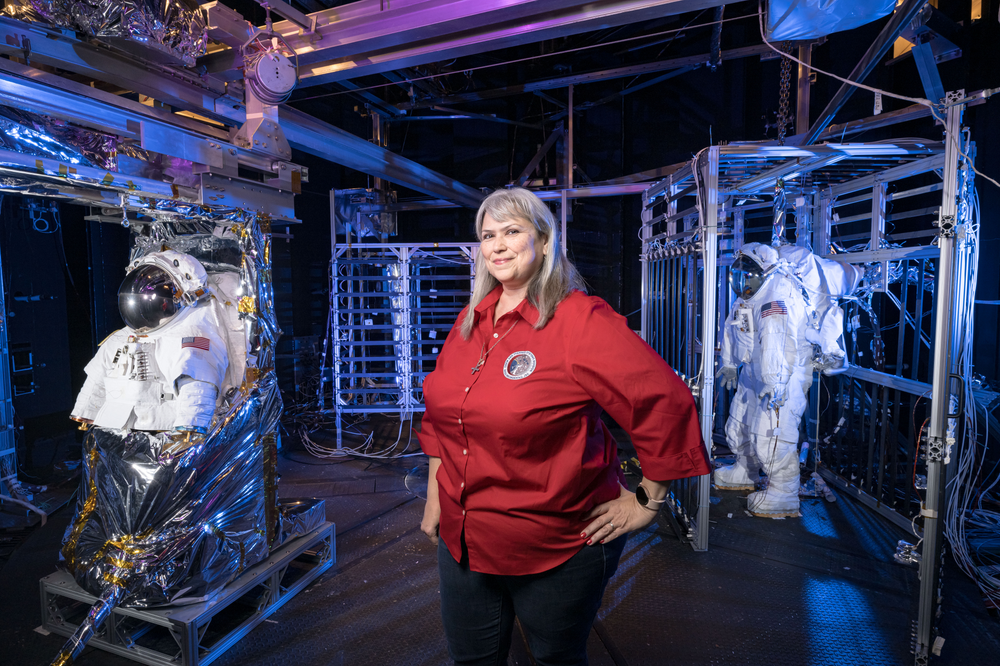 A NASA employee stands in a spacesuit test chamber.