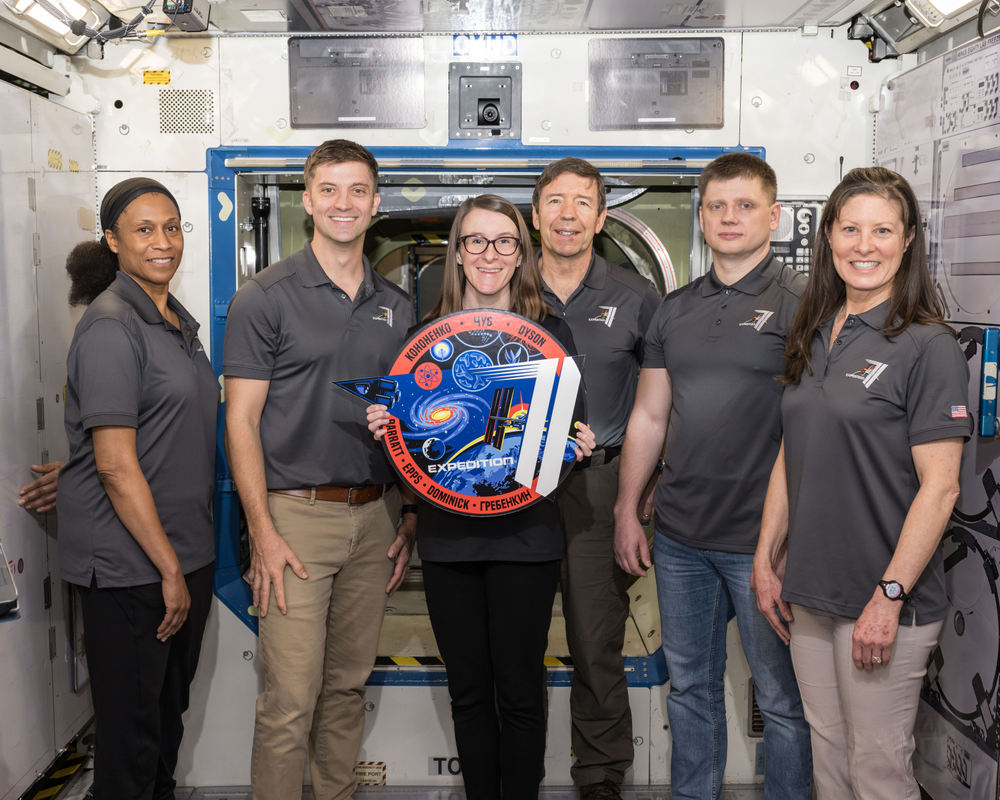 A NASA trainer poses for a group photo with members of the ISS Expedition 71 crew.