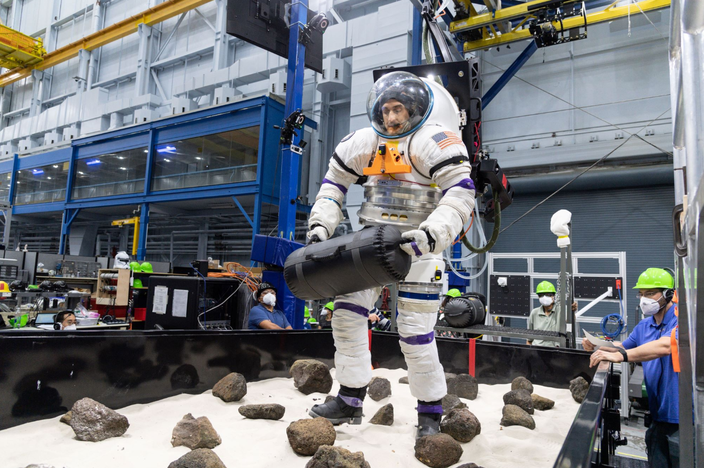 A volunteer from NASA’s Artemis Extravehicular Activity training group moves a 30-pound object through a boulder field while in a spacesuit and connected to NASA’s Active Response Gravity Offload System, or ARGOS. He is conducting a trial run through an obstacle course while ARGOS lifts him and the suit in a way that simulates gravity similar to that on Mars. Some astronauts will work through this obstacle course immediately after returning to Earth so that researchers can learn more about how mission-ready a crew can be after landing on a planet’s surface. Credit: NASA