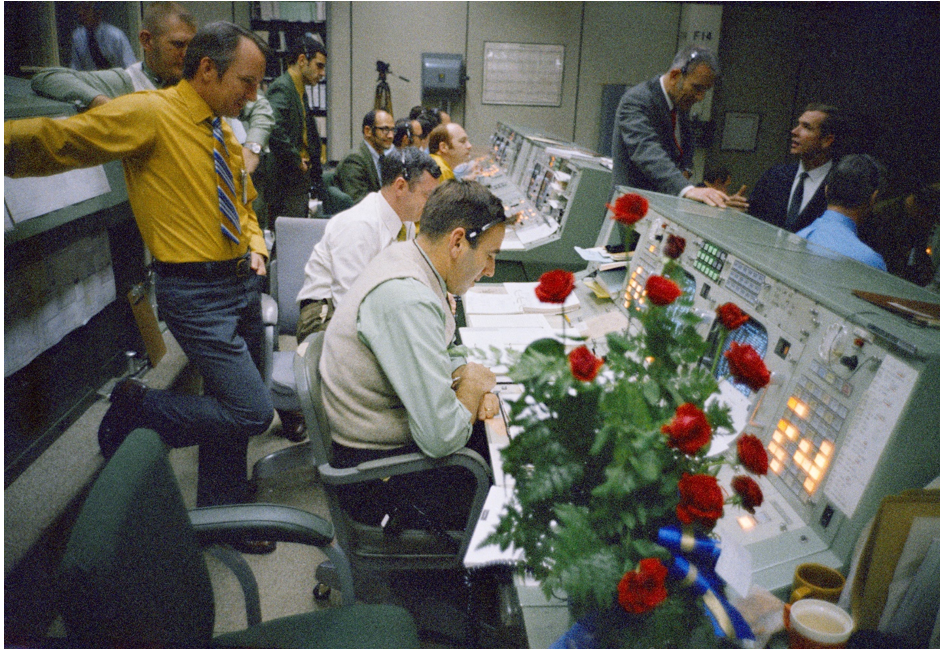 In a tradition dating back to Apollo 8, Cindy Diane of Montreal, Canada, sent a bouquet of red roses to the Mission Control Center at the Manned Spacecraft Center. This bouquet arrived during Apollo 14’s eighth day in space. Flight Directors Gerald D. “Gerry” Griffin, standing at left, Glynn S. Lunney, and Milton L. Windler monitor the progress of the mission. Credits: NASA