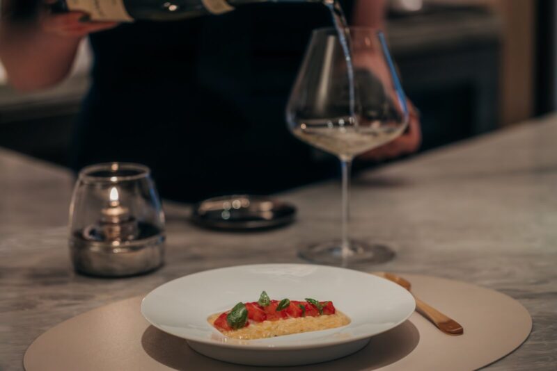 Elegantly plated dish with wine being poured into a Burgundy wine glass 